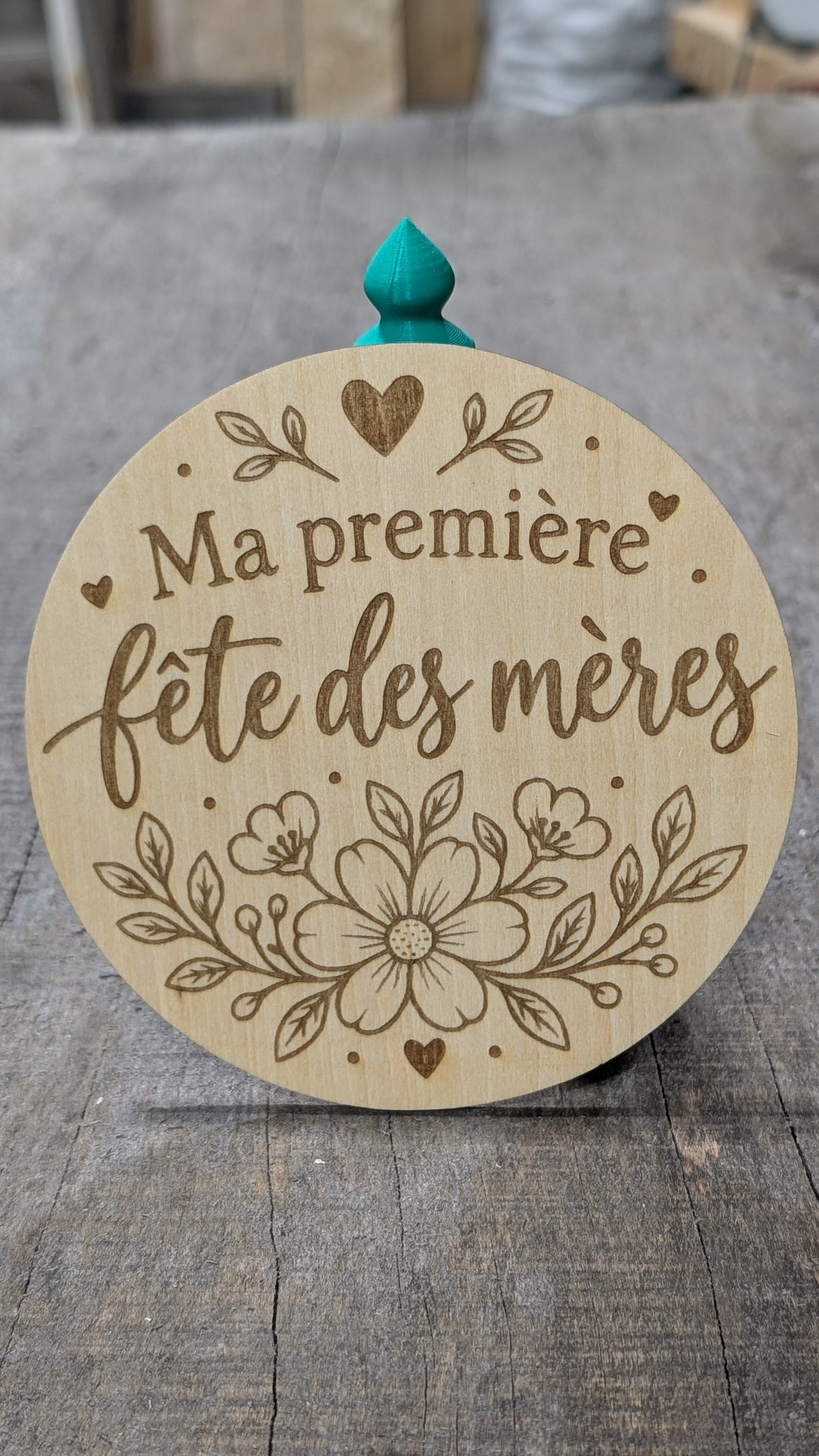 Pastille en bois gravé « Ma première fête des mères », avec cœur et bouquet de fleurs.