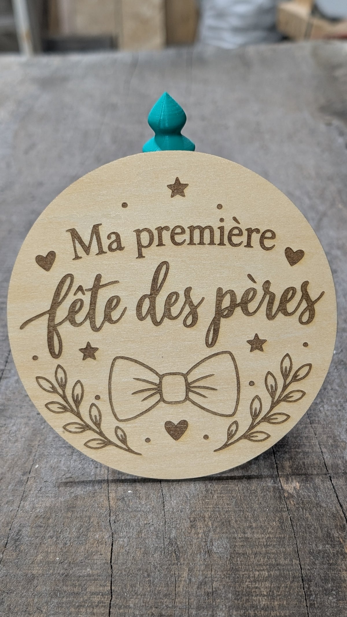 Pastille en bois gravé « Ma première fête des pères », avec nœud papillon et feuillage.