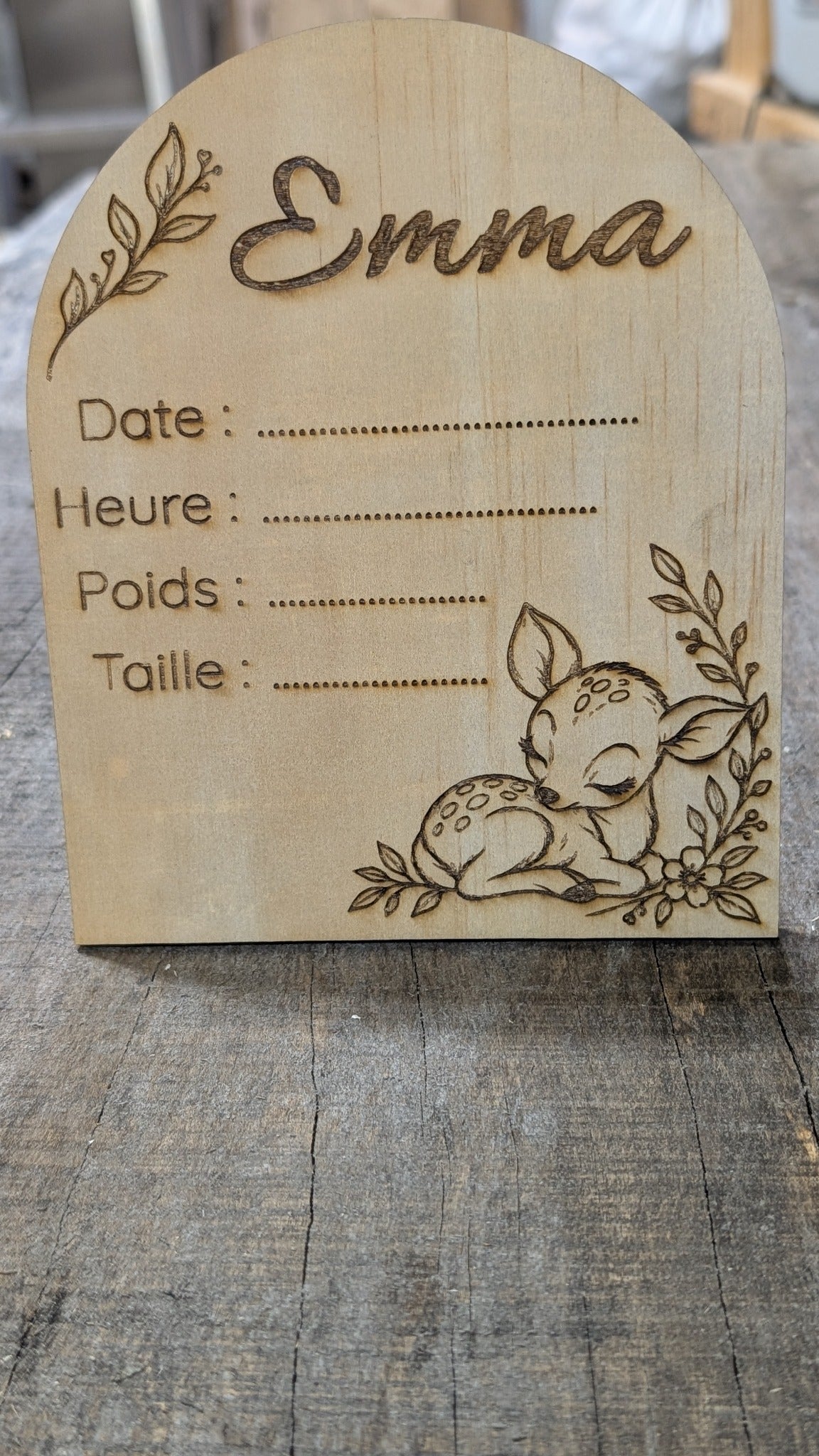 Plaque de naissance en bois en forme d’arche, prénom Emma, faon endormi et feuillage, avec espaces pour les informations de naissance.