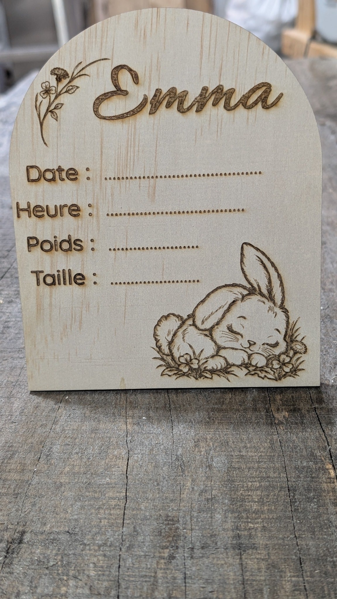 Plaque de naissance en bois en forme d’arche, prénom Emma, lapin endormi et fleurs, avec espaces pour les informations de naissance.